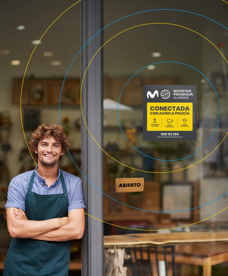 Comerciante en la puerta de su tienda con la placa de Movistar Prosegur Alarmas