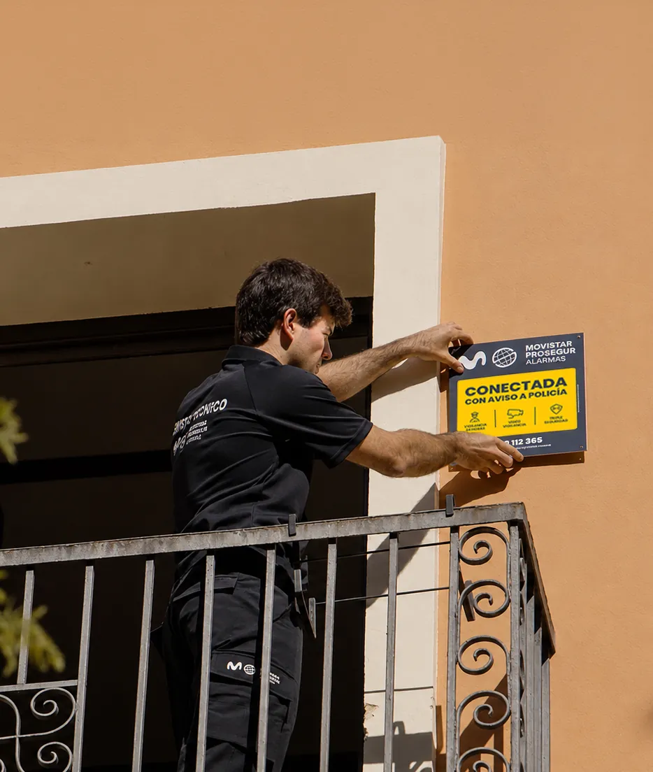 Técnico colocando la placa de Movistar Prosegur Alarmas en una vivienda